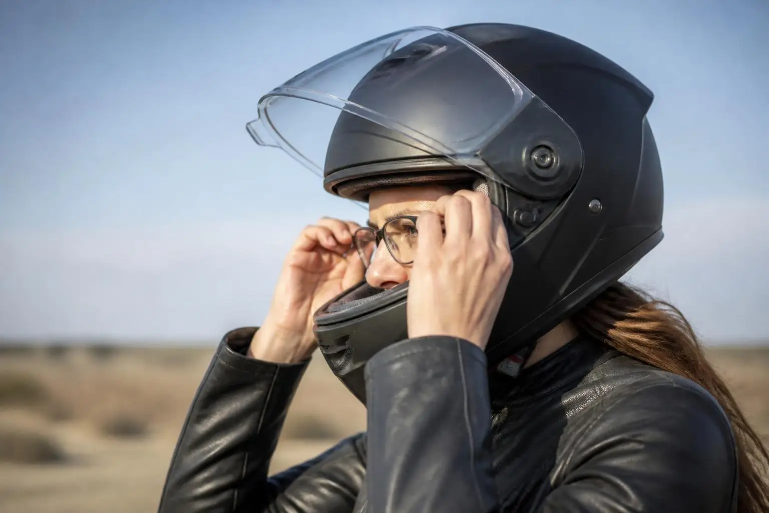 Fahrerin setzt vor der Fahrt eine Brille unter dem Helm auf.